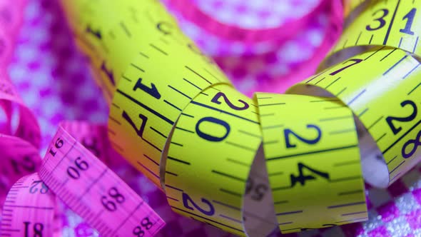 Close Up of a Pink and Yellow Measure Tape on Colored Rotating Background