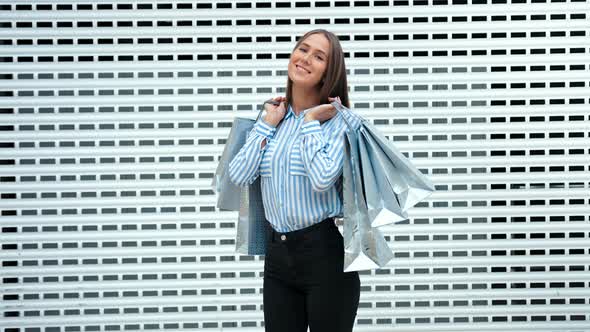 Fashion Blonde Model with Bags Looking at Camera and Smiling After Shopping in the Modern Light Mall