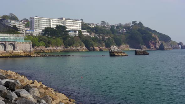 Panning shot revealing the rugged coasts and cliffs of Torquay and Torbay with the rock arch London