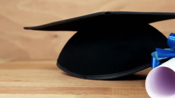 Close-up of graduation certificate with mortar board on a table