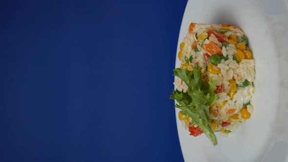 Rice with Vegetables in a Rotation Plate on a Blue Background