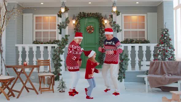 Cheerful Old Grandparents with Granddaughter Child Kid Dancing Around Decorated Christmas House Tree