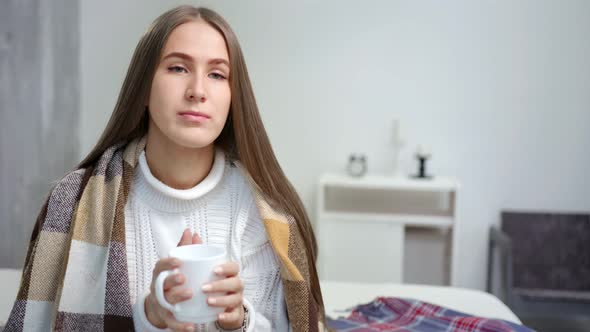 Portrait of Young Attractive Woman Wrapped in Warm Plaid Holding Mug Drinking Hot Beverage