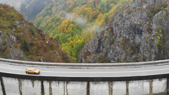 Aerial Shot of Car Riding at Dam in Autumn Mountain Road