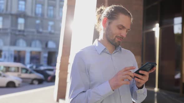 Business Man Using Mobile Phone Outdoors On Sunny Day At Street