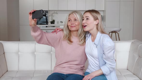 Happy Affectionate Mature Mother and Grownup Daughter Make Selfie Video Call By Mobile Phone While
