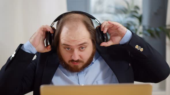 Young Businessman Listening Music in Headphones While Working on Laptop in Laptop