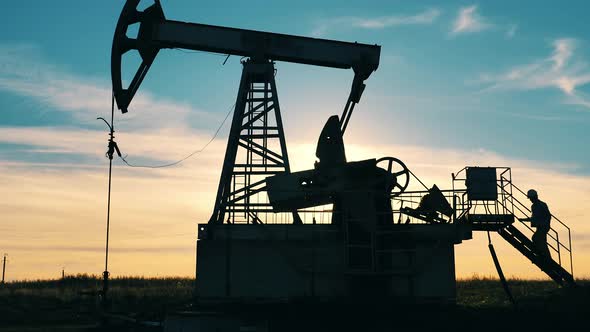 Oil Industry Worker Walking Up To an Oil Pumpjack in an Oil Field