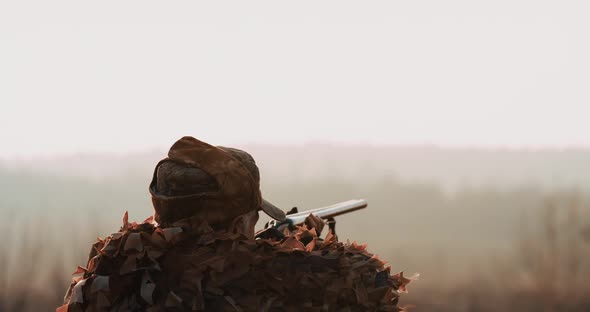 Hunter Aims the Target with Hunting Rifle in Sunset Light