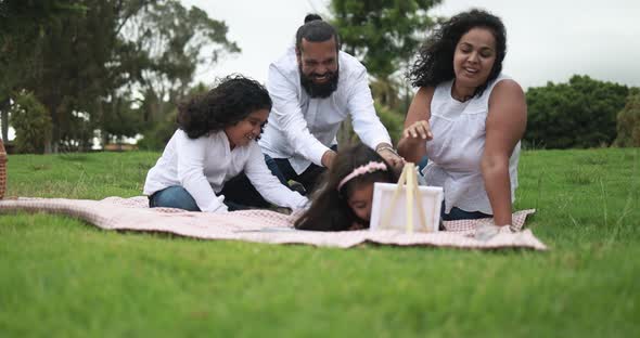 Indian parents having fun at city park painting with their children - Family, summer and love 