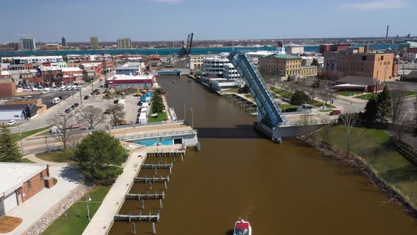 Boat on river with drawbridge open on the Black River in Port Huron, Michigan with drone videoing fo