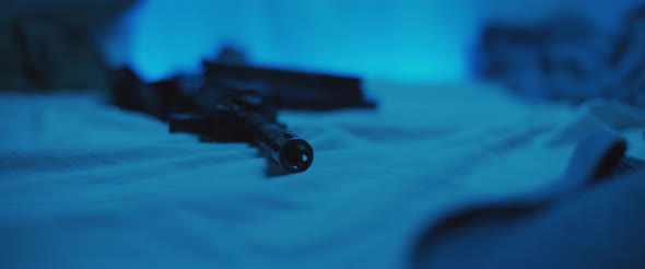 Close up of M16 rifle lying on a bed. Military, PTSD soldier concept. Cinematic handheld shot.