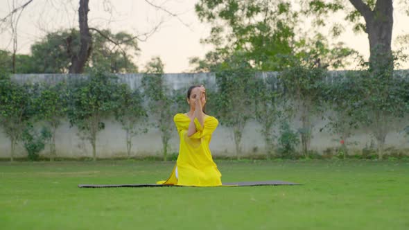 Eagle Yoga pose or Garudasana is being done by an Indian woman in a park