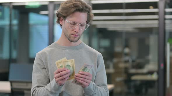 Portrait of Young Businessman Counting Dollars