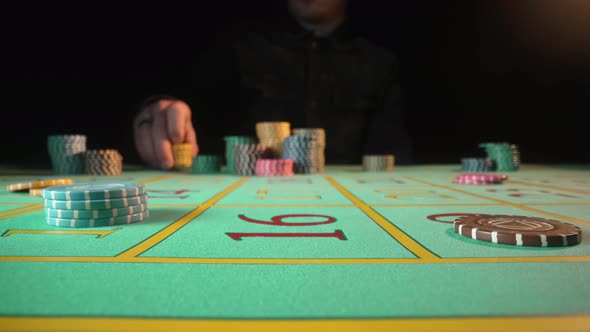 Unrecognizable Male Gambler Makes Bets While Sitting at a Roulette Table in a Casino