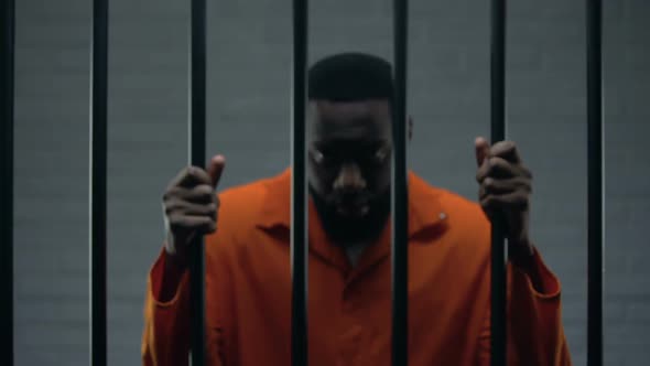 African-American Male Prisoner Holding Bars and Looking to Camera, Imprisonment