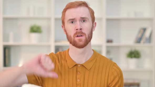 Portrait of Disappointed Redhead Man Doing Thumbs Down 