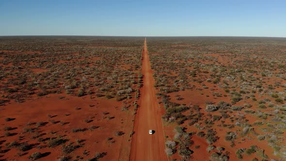 Traveling a red sand road in the wild Australian outback. Car lost in the endless desert