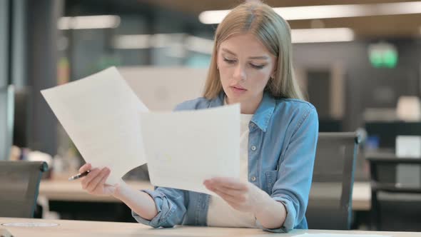 Young Woman Reading Documents in Office