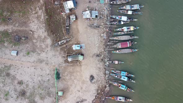 Aerial top down shot showing fishing boats parking on deck beside ghetto poor quarter in Phnom Penh