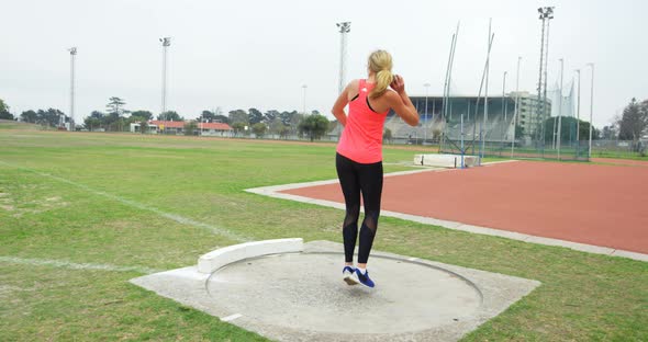 Rear view of Caucasian female athlete practicing shot put throw at sports venue 4k