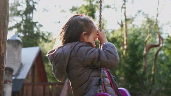 Little Girl Spinning on a Swing in the Spring Forest