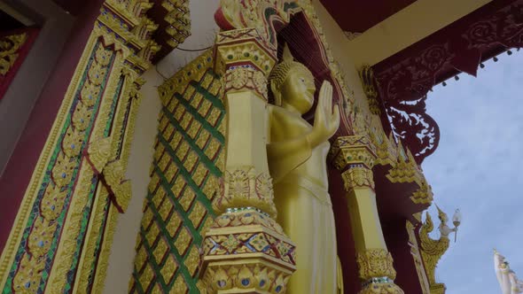 Standing Golden Buddha sculpture at the Plai Laem temple in Koh Samui panning shot low angle view