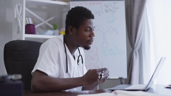 Side View Confident African American Scientist Conferencing Online Sitting at Table with Laptop with