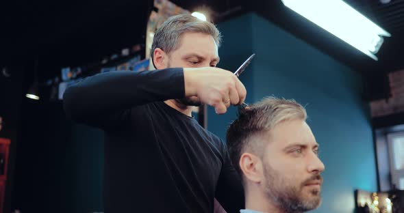 Male Barber Making Client Haircut with Scissors