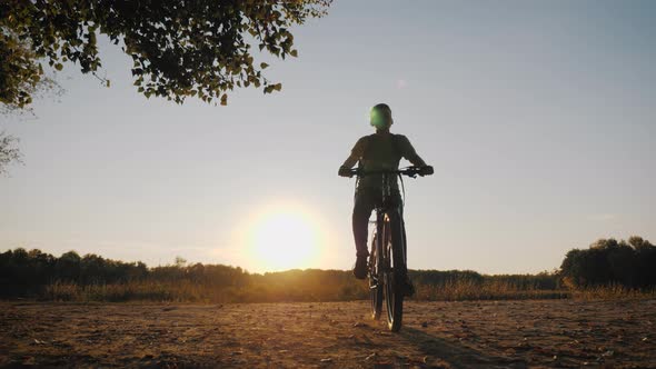 Teenage Boy Rides Bike in City Park at Sunny Day. Healthy Lifestyle Concept