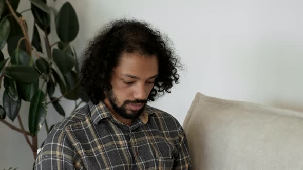 Close up of handsome man using laptop on sofa in living room. Working from home. Social distancing