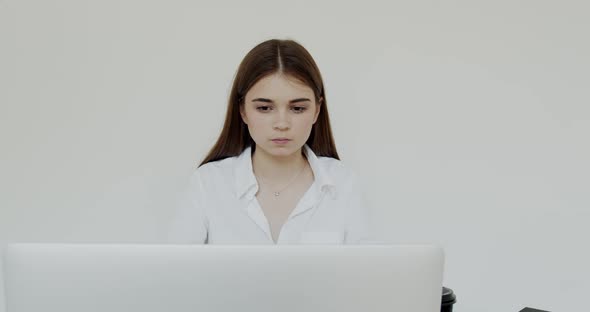 Portrait of Young Girl Reading on Laptop at Camera on Background in Office