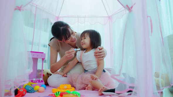 Asian beautiful mother play education game with kid to learn and develop skill in tent at house.