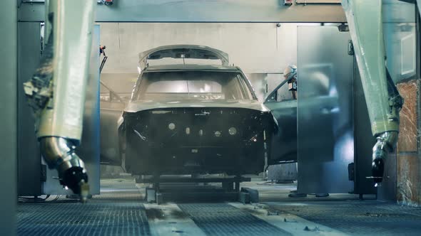 Factory Workers Painting a Car Body at a Car Factory