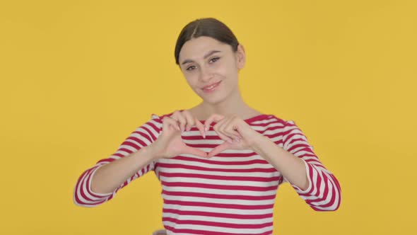 Spanish Woman showing Heart on Yellow Background