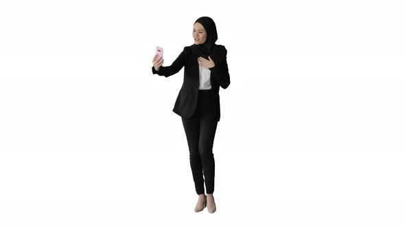 Young Pretty Muslim Woman in Hijab Having Video Call on Her Phone As She Walks on White Background.