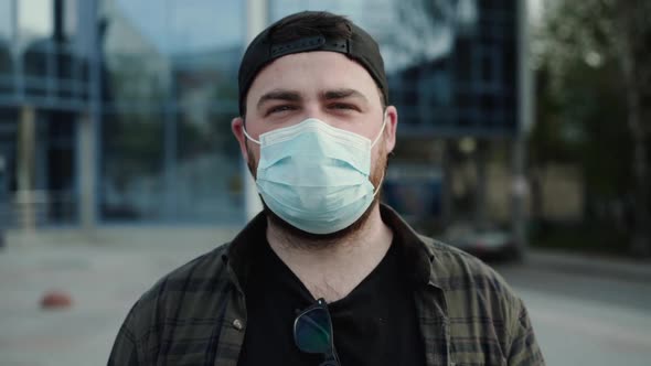 Young Man in Casual Clothes in Medical Mask Talking Into Camera with Gestures