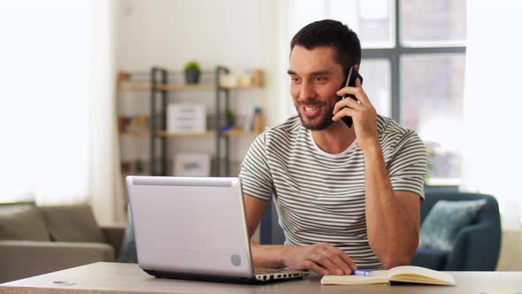 Man with Laptop Calling on Phone at Home Office