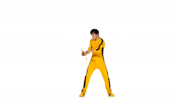 Man in Yellow Suit Training Karate and Expertly Twirling Nunchaku