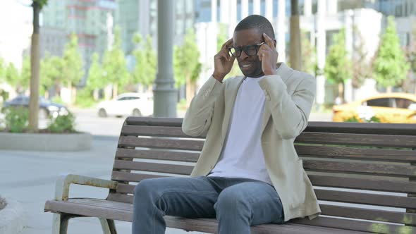 African Man with Headache Sitting Outdoor on Bench