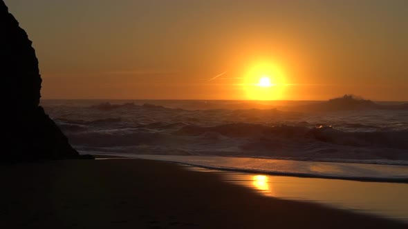 Sunset Shining Above Small  Waves Crashing on the Beach