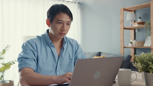 Asia guy casual wear using laptop online learning in living room at house. Working from home.