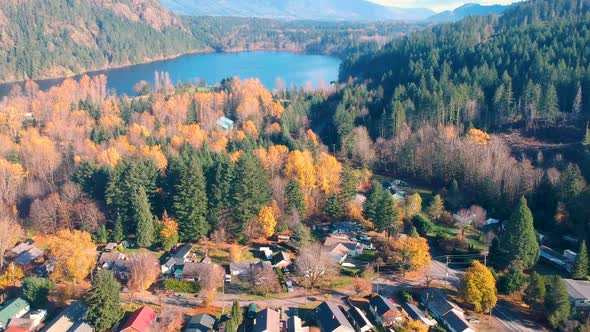 Drone shot of small town with lake and mountains in background in the fall.