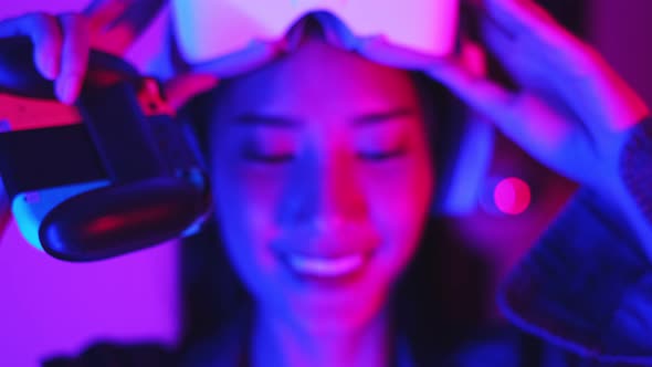 Young asian woman is using virtual reality headset. Neon light studio portrait.