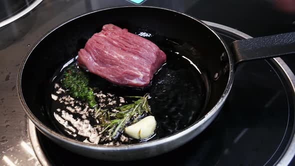 Large Steak Is Fried in a Frying Pan in the Kitchen of the Restaurant in Close-up