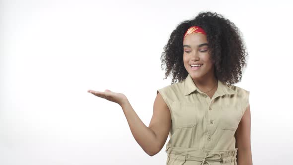 Confident Pretty Africanamerican Young Curlyhaired Woman Introduce Something Over White Background