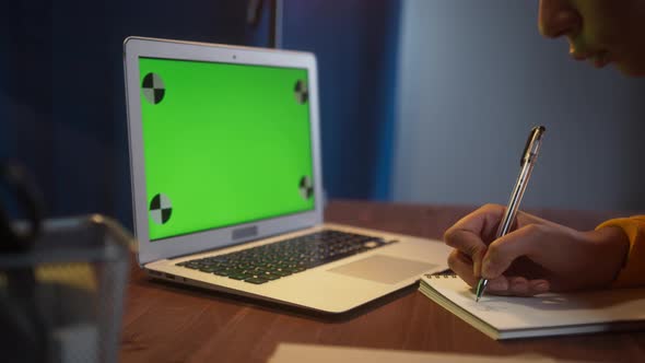 Beautiful Black Woman Sitting at Her Desk Works on a Laptop with Green Chroma Key Mockup Screen