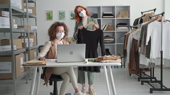 Online Trade Young Work Team in Medical Masks Sell Dresses Via the Internet Chatting with a Client