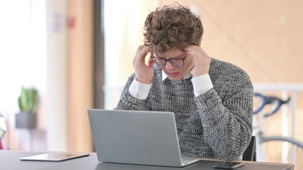 Young Man with Headache Using Laptop at Work