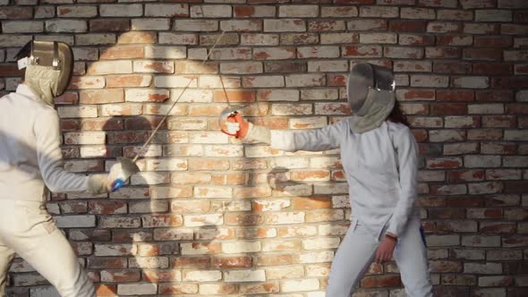 Man and Woman Are Fencing in a Training Hall, Hitting with Rapiers